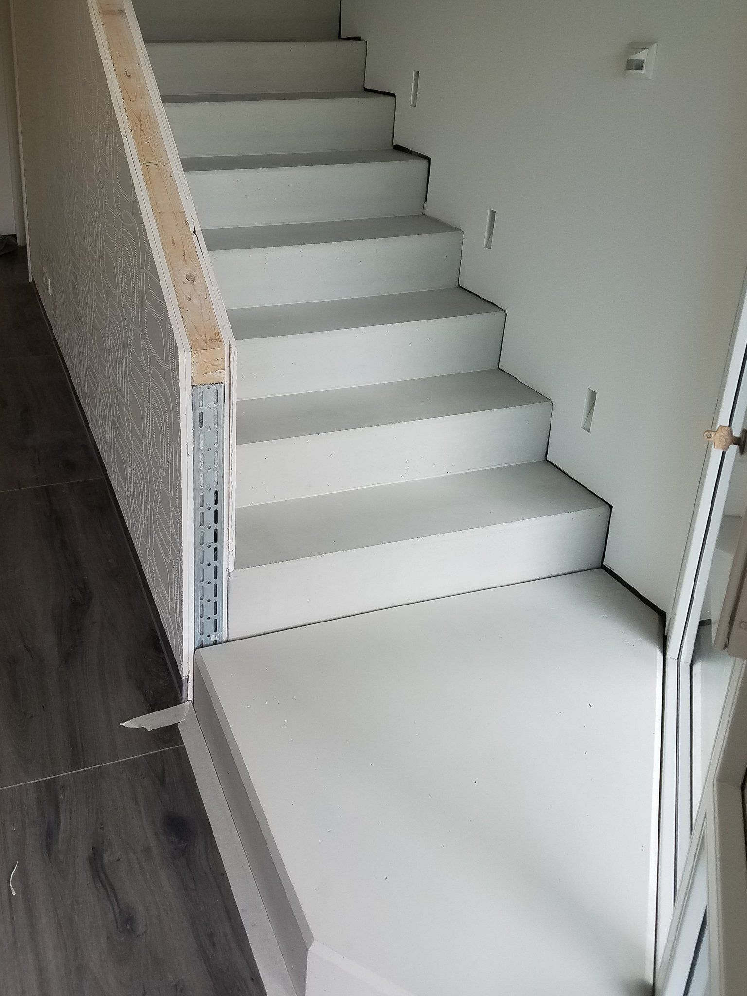 Ein Treppenlauf und Podest hellgrau verschönert mit Betonkosmetik von rauMKult Sichtbeton, links sind Großformatike Fließen