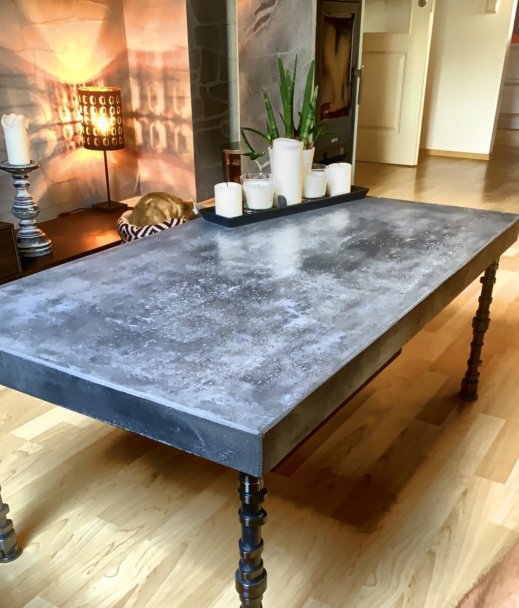 ein Beschichteter Tisch mit Anthrazit farbenen Mikrozement von rauMKult Sichtbeton, auf dem Tisch stehen 5 weiße Kerzen, der Tisch steht auf einem hellen Holzfußboden