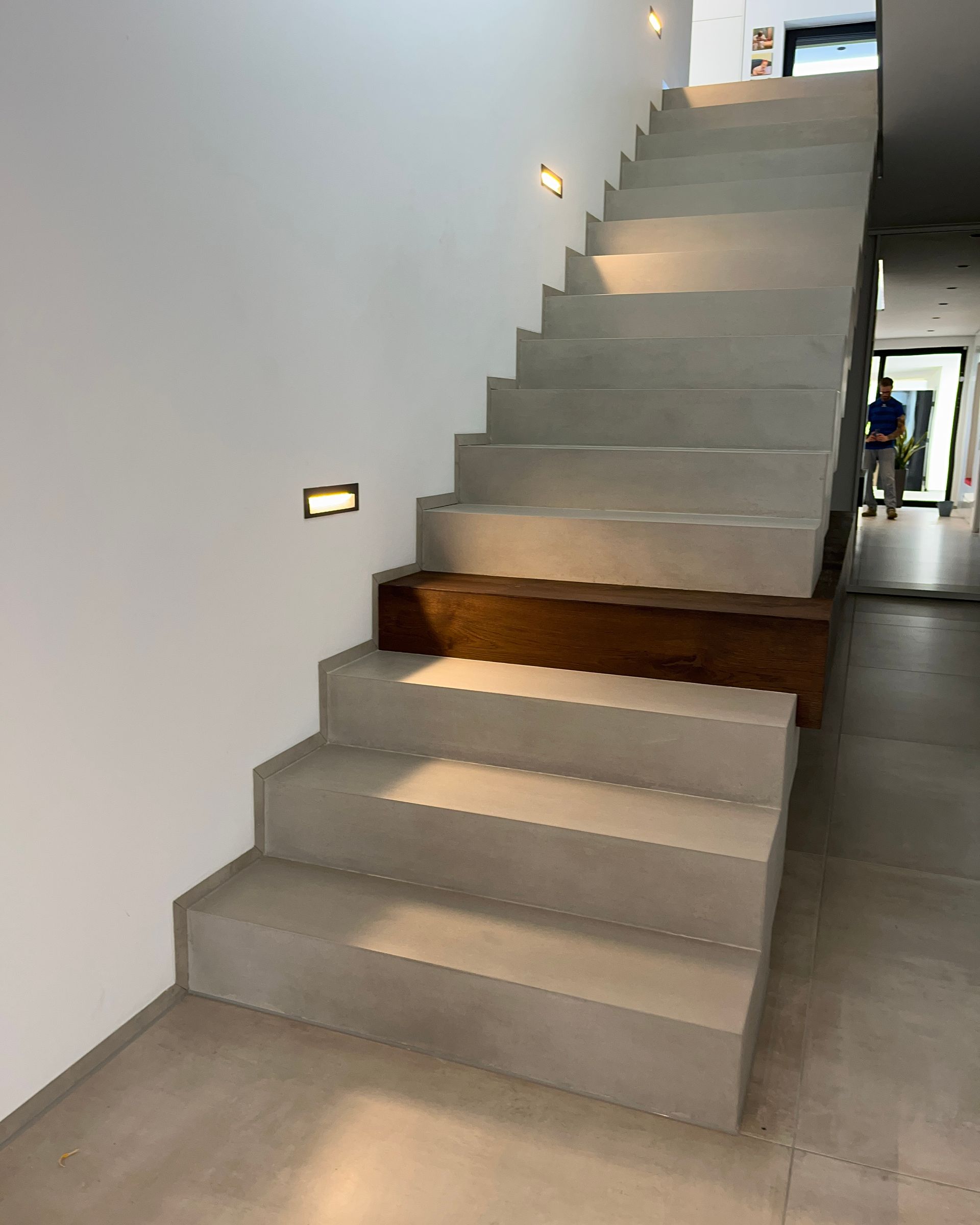 Eine Sichtbetontreppe in Grau mit einer braunen Holzstufe als Akzent