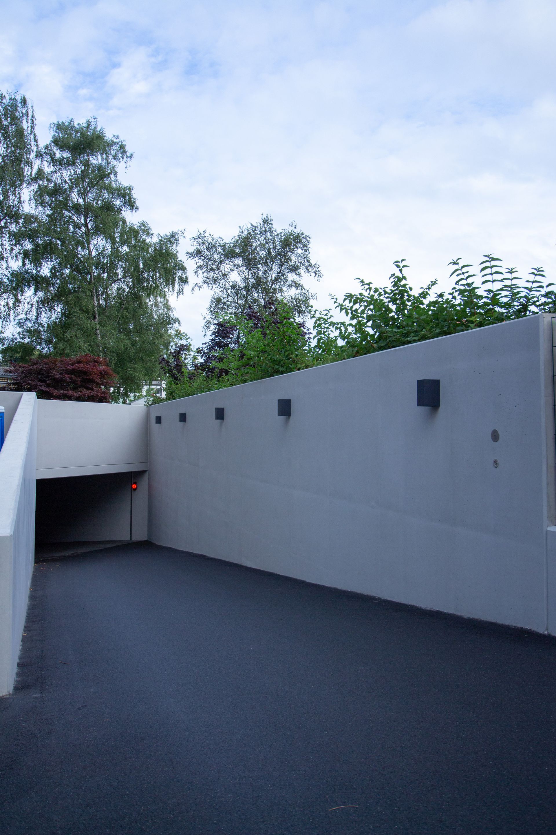 Beton Mauerwände im Außenbereich einer Tiefgaragen Einfahrtin Grau mit schwarzer Beleuchtung 