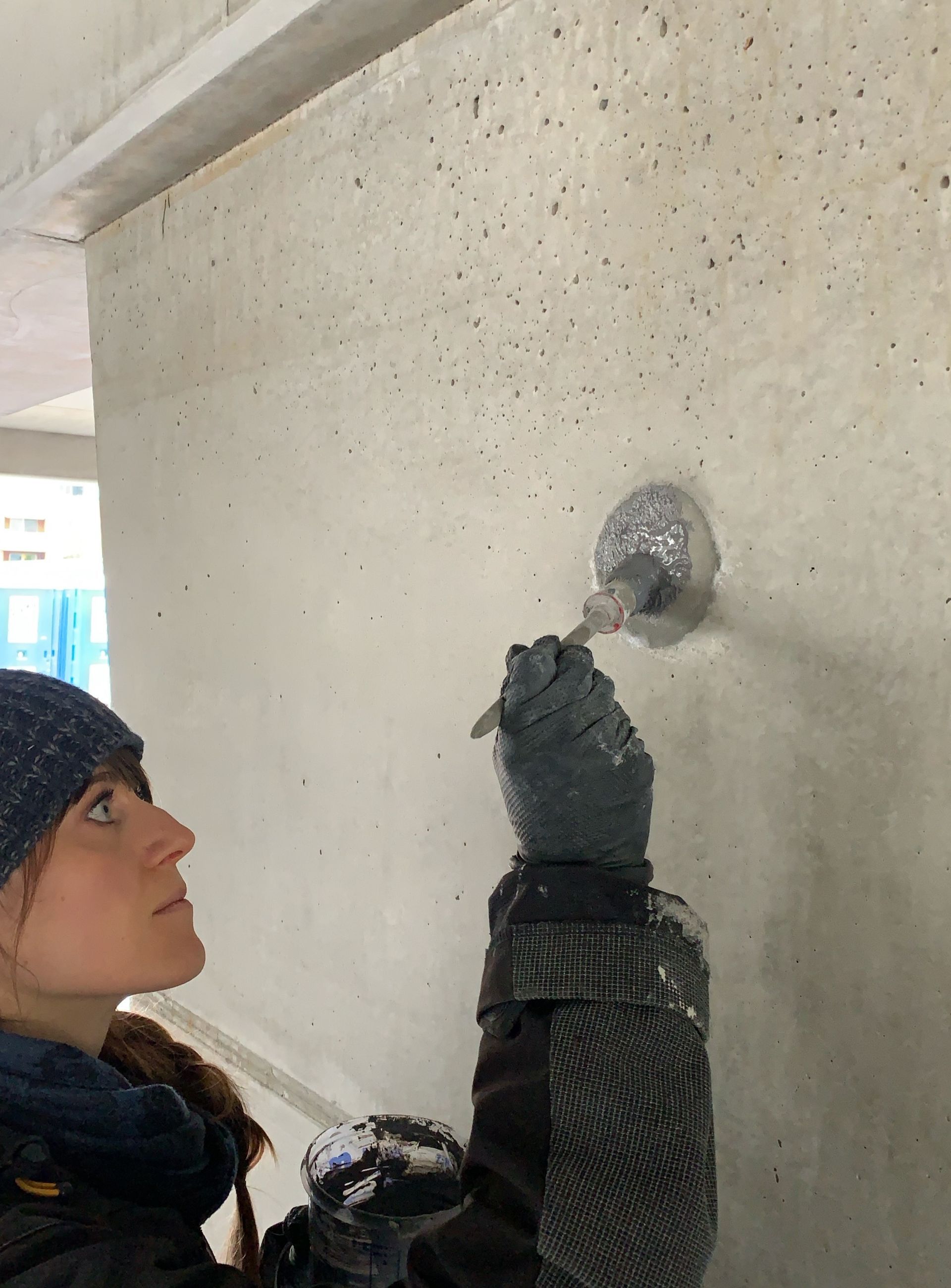 Eine Betonkosmetikerin bearbeitet Sichtbeton an einer Betonwand