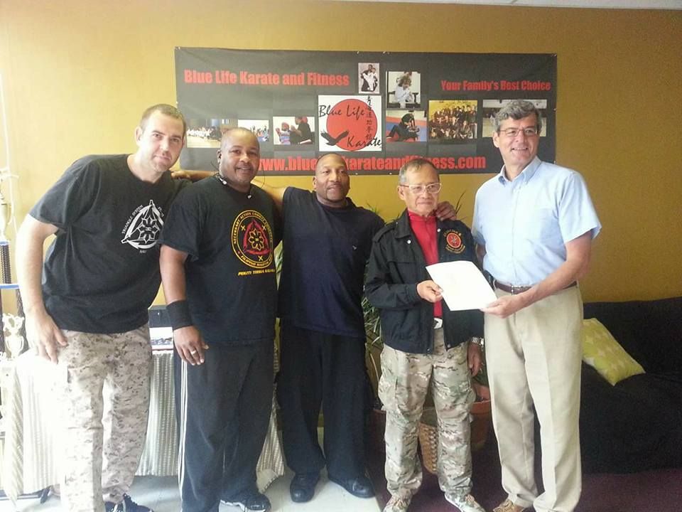 A group of men standing in front of a sign that says urban life karate and fitness