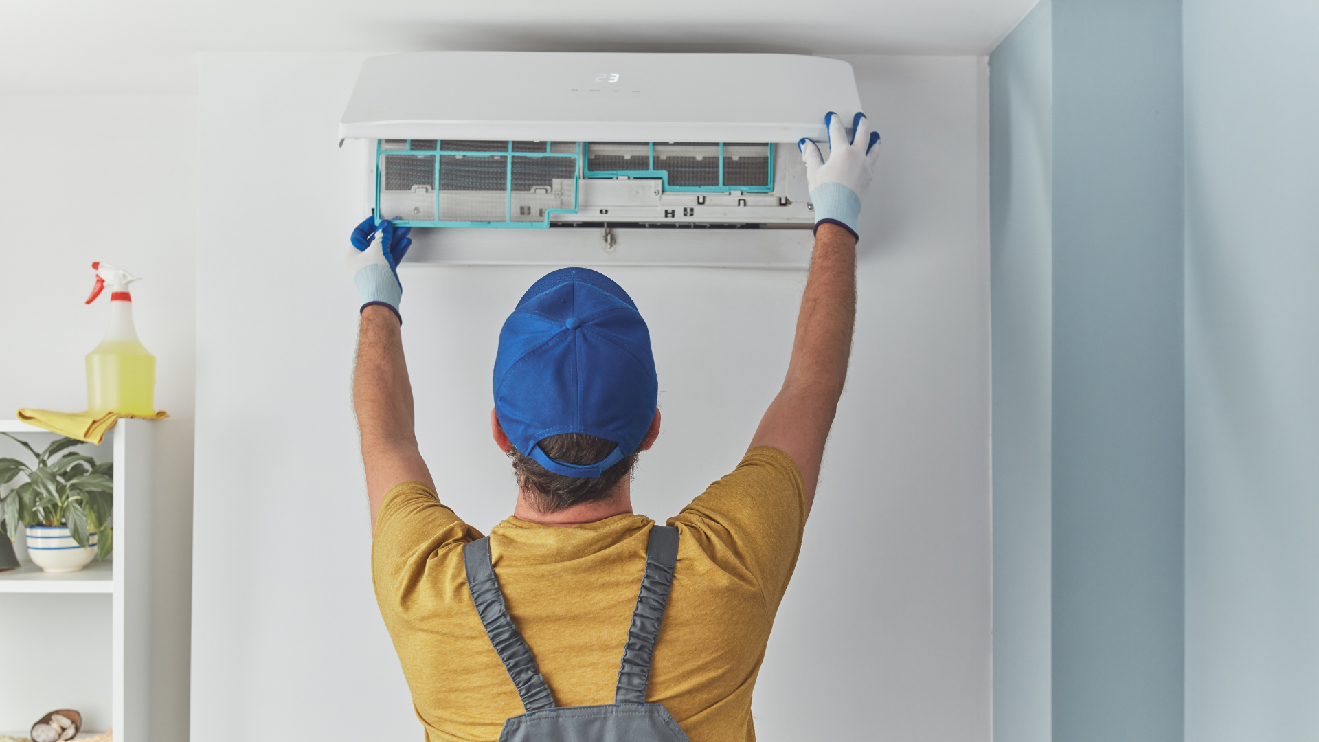 A man is cleaning an air conditioner in a living room.