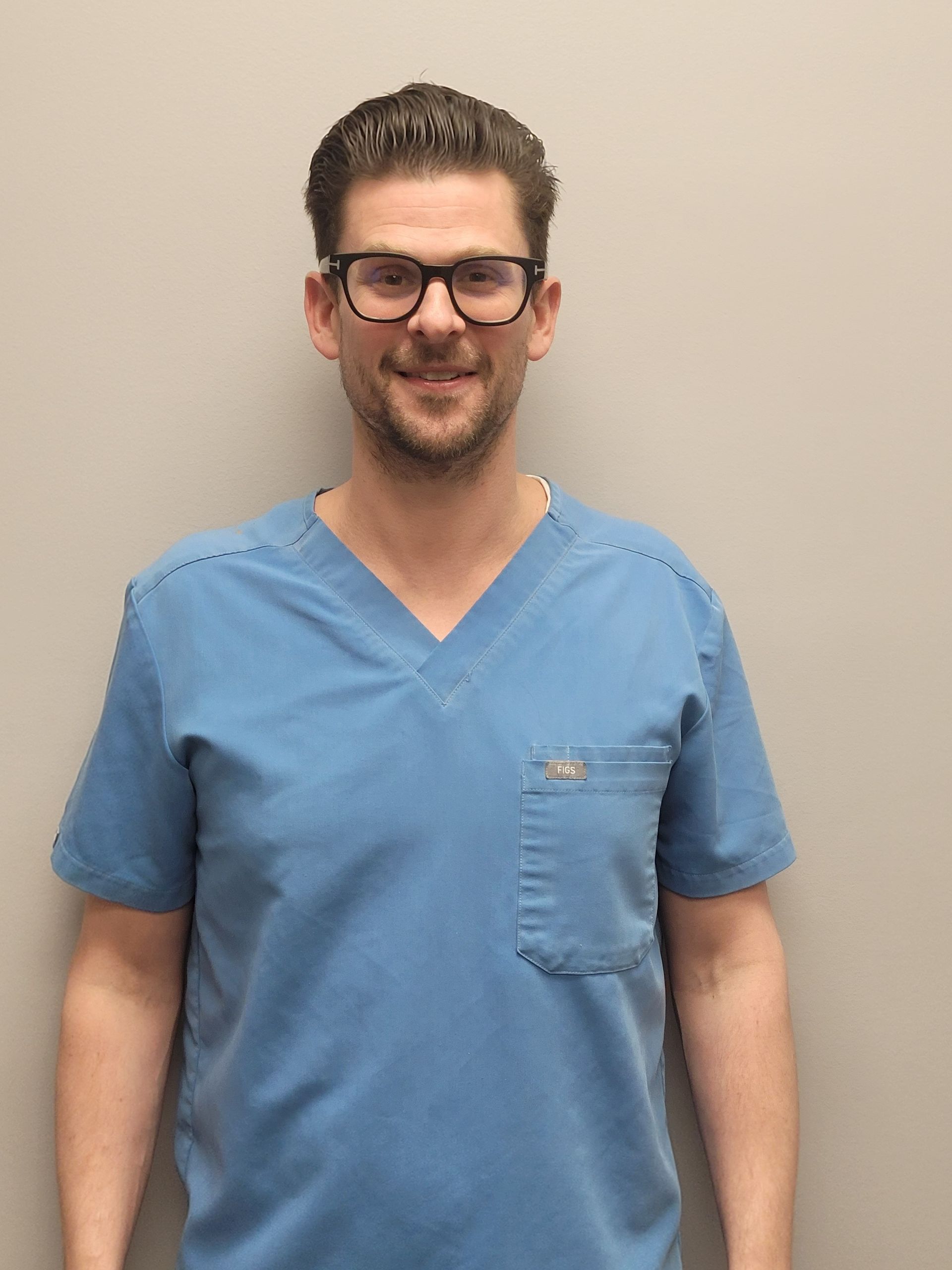 A smiling doctor in a lab coat with a stethoscope around his neck.