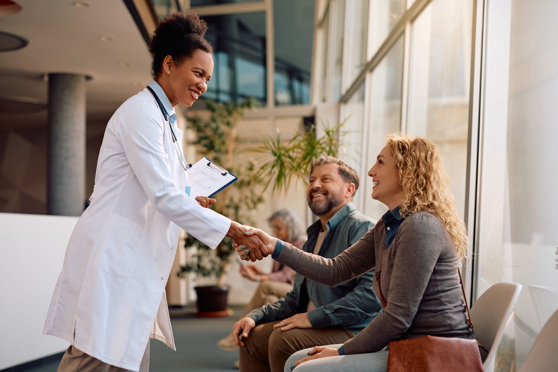 A smiling doctor in a lab coat with a stethoscope around his neck.
