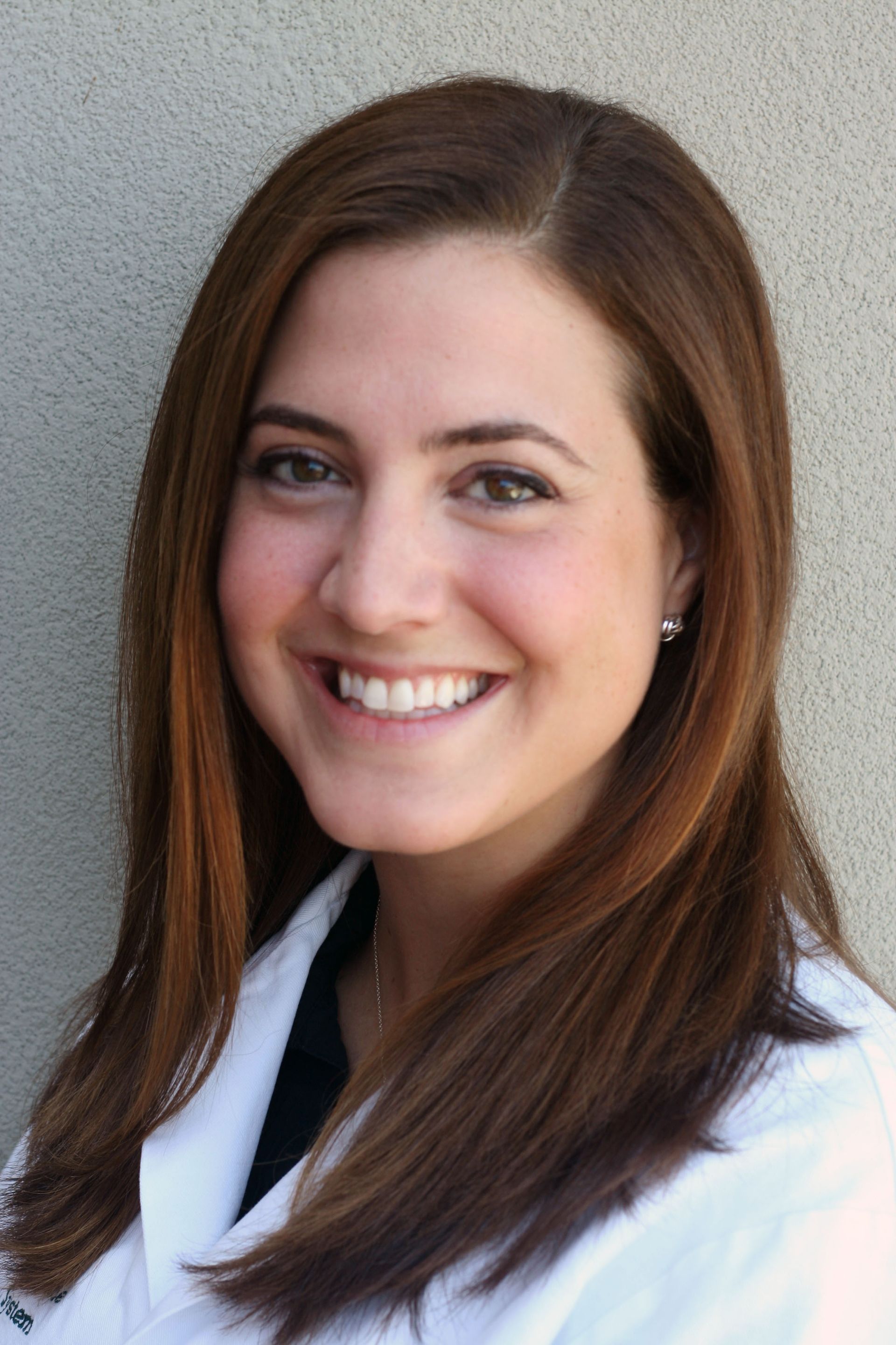 A smiling doctor in a lab coat with a stethoscope around his neck.