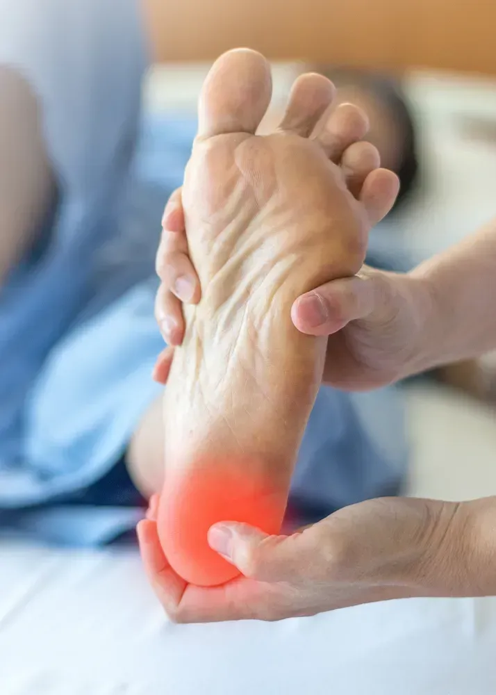 A person holding another person's foot, highlighting a painful red area on the heel.