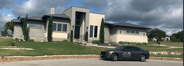 Modern house with a gray car parked in front of it under a cloudy sky.