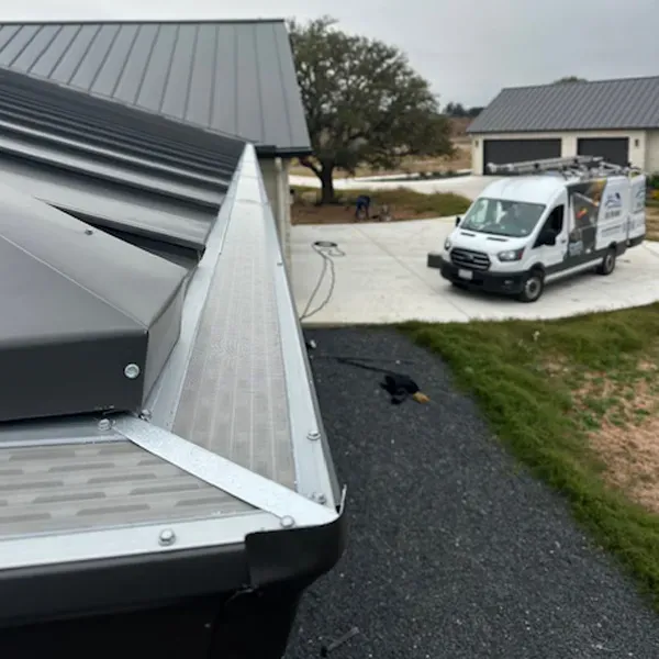 Metal roof with gutter guard and service van parked on driveway.