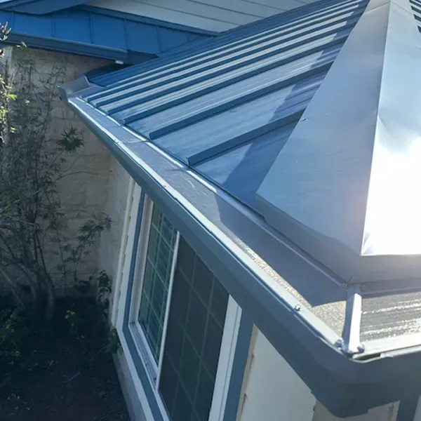 Blue metal roof with matching gutters and a window.