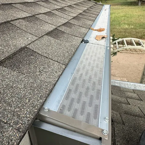 A close-up of a gutter with a metal mesh filter installed to prevent debris from entering.