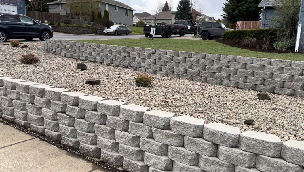 A brick wall is surrounded by gravel in a yard.