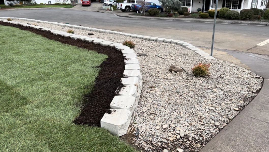 A lush green lawn is surrounded by a stone wall and gravel.