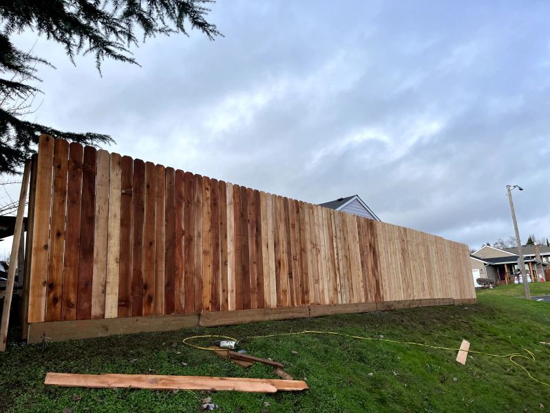 A wooden fence is being built in a grassy field.