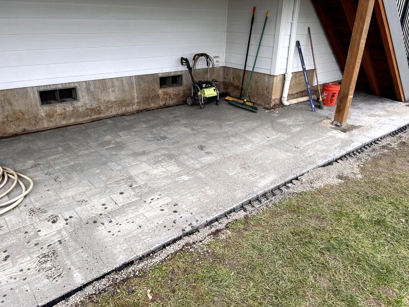 A concrete patio with tools and a hose in front of a house.