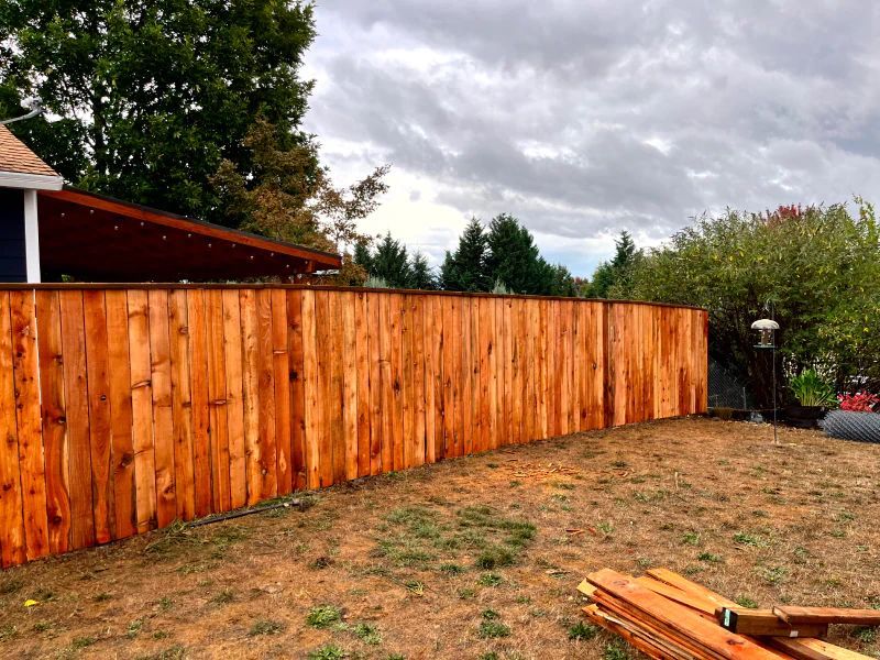 A wooden fence is being built in the backyard of a house.