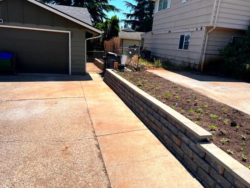 A driveway with a brick wall and a house in the background