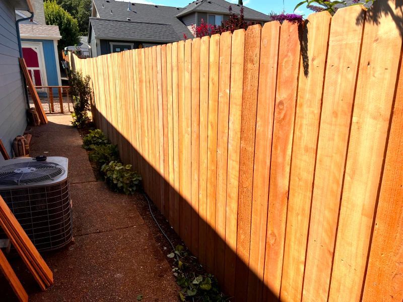 A wooden fence is in the backyard of a house.