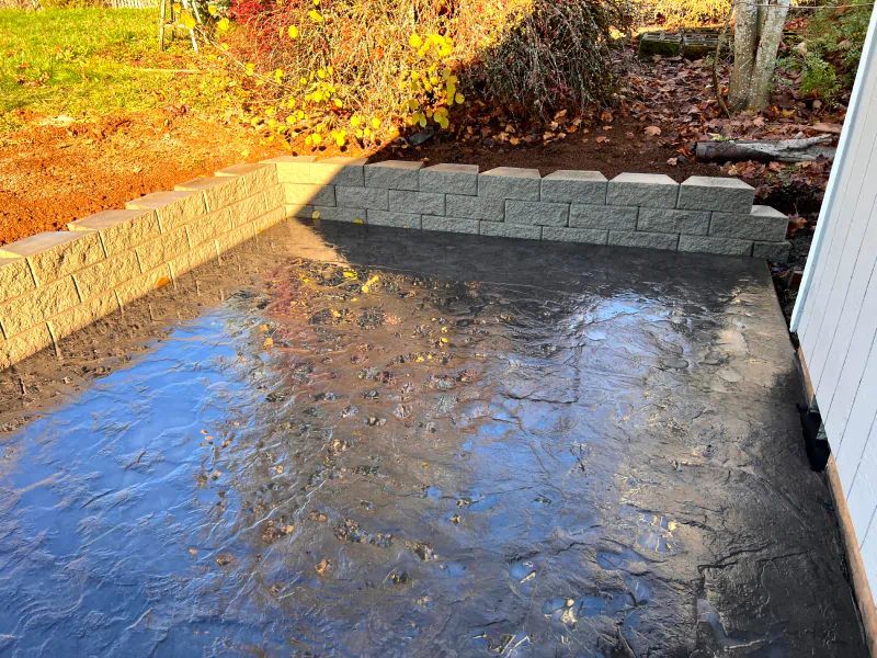 A concrete walkway leading to a brick wall next to a house.
