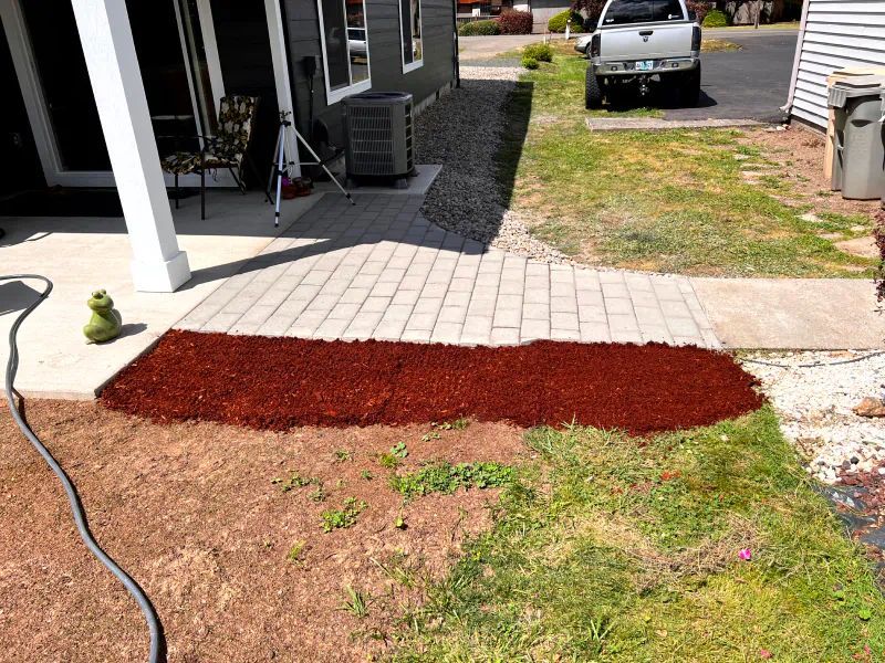 A white truck is parked in front of a house next to a sidewalk.