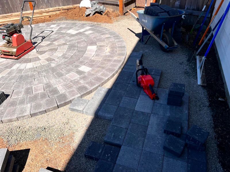 A circular patio is being built with bricks and a wheelbarrow.