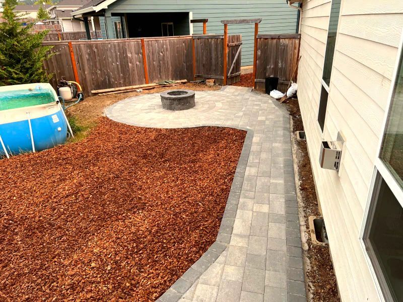 A patio with a fire pit and a pool in the backyard of a house.