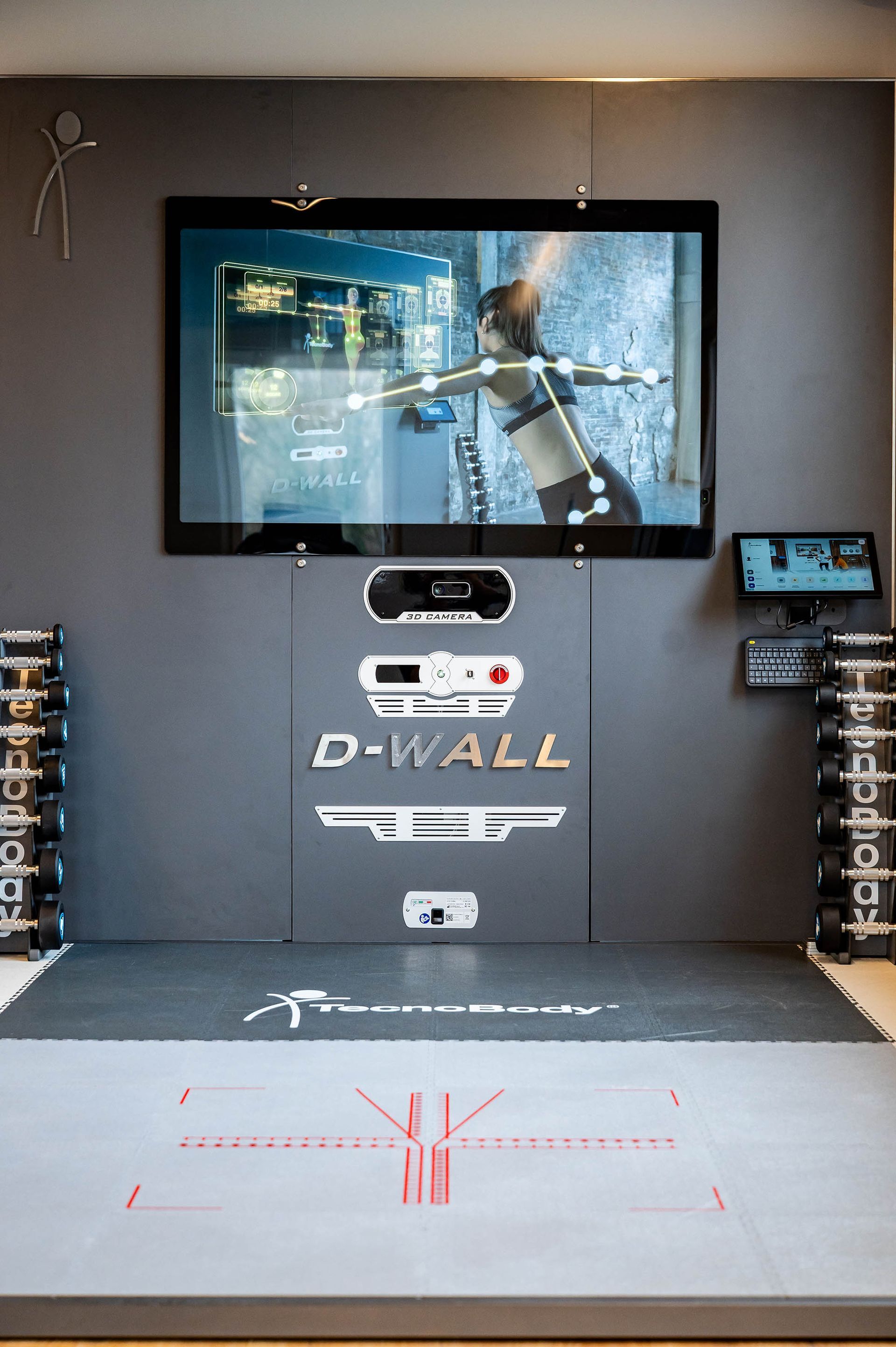 In einem Fitnessstudio hängt ein großer Flachbildfernseher an der Wand.