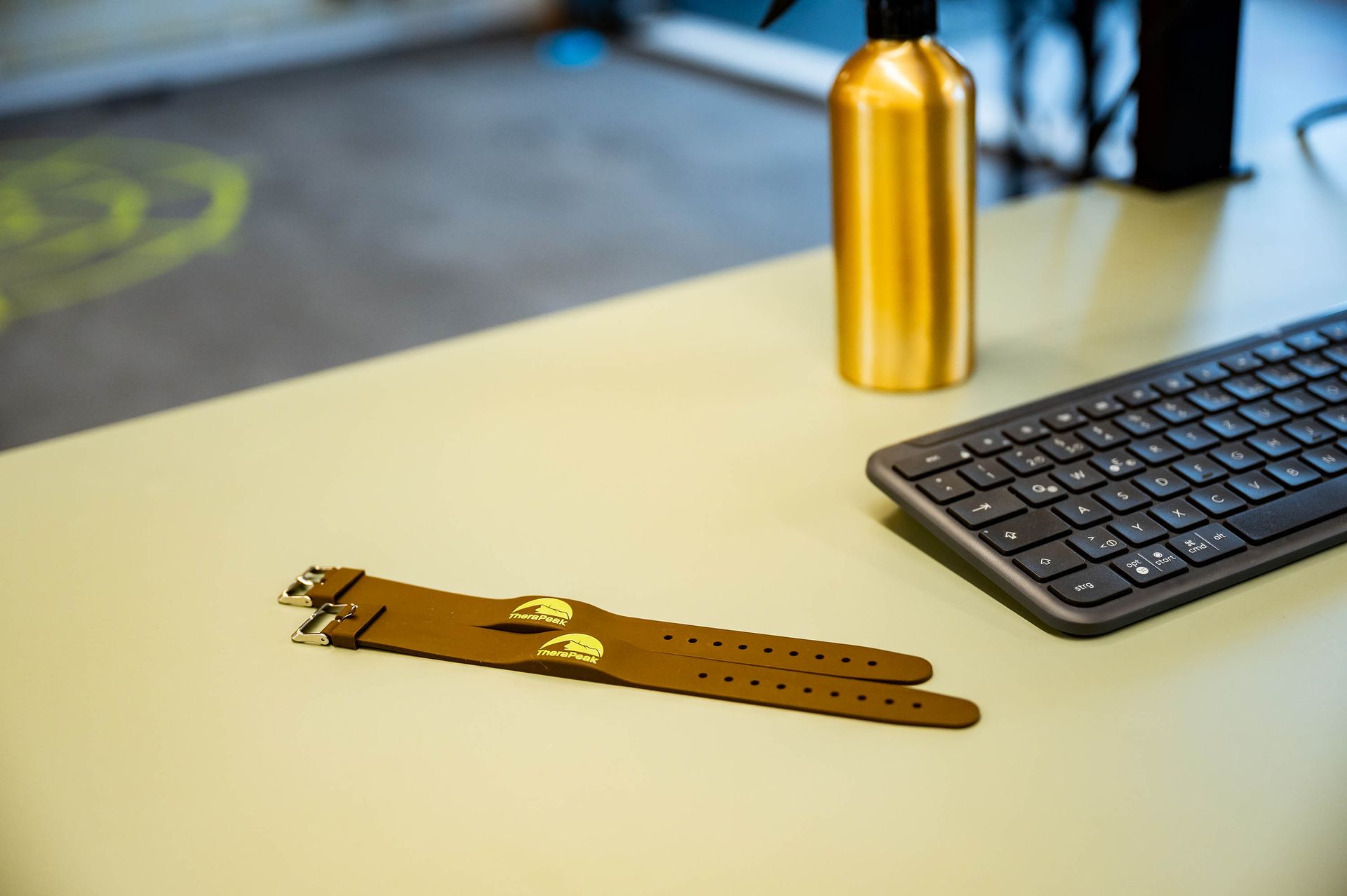 Auf einem Schreibtisch stehen eine Tastatur und eine Wasserflasche.