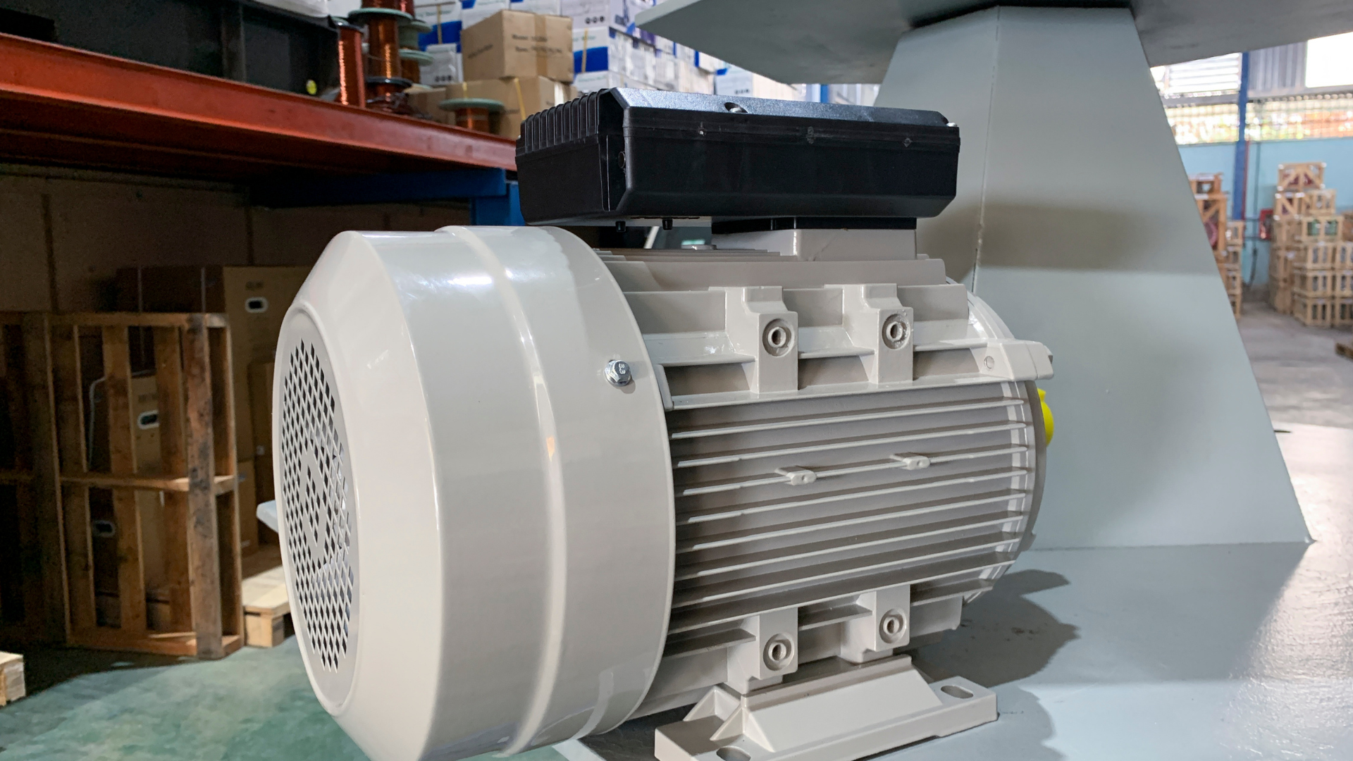 A white motor is sitting on the floor in a warehouse.