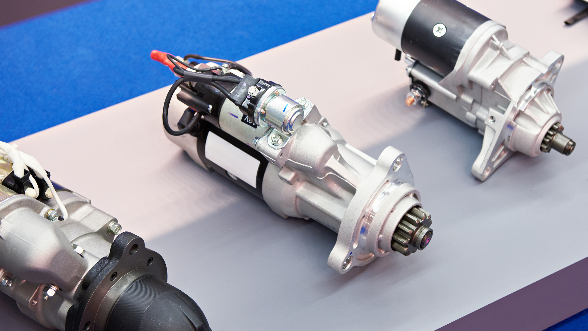 Three different types of starter motors are sitting on a table.