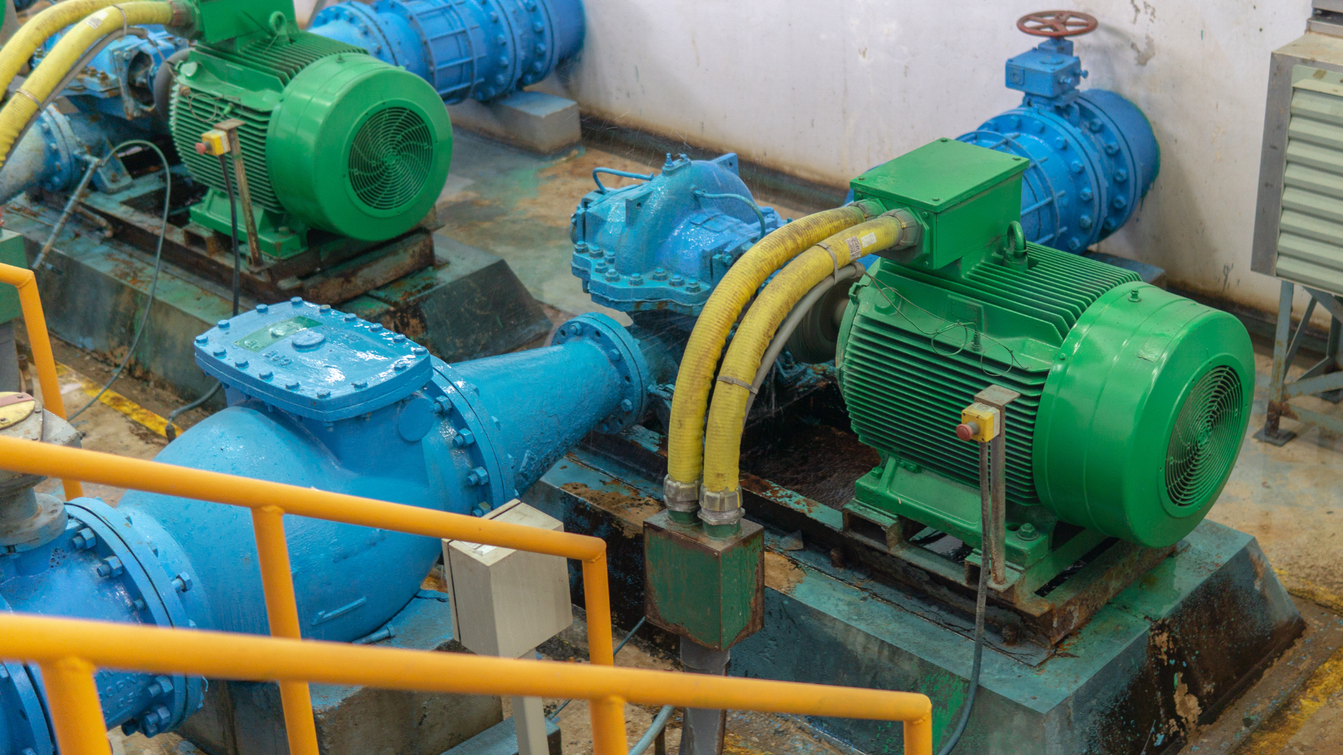 A group of green and blue water pumps are sitting next to each other in a room.