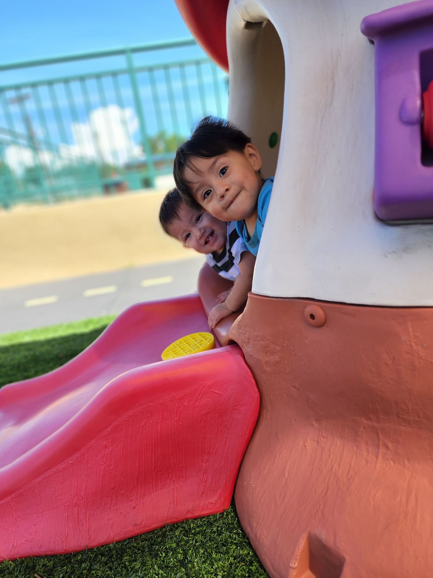 two children are playing on a slide in a playground
