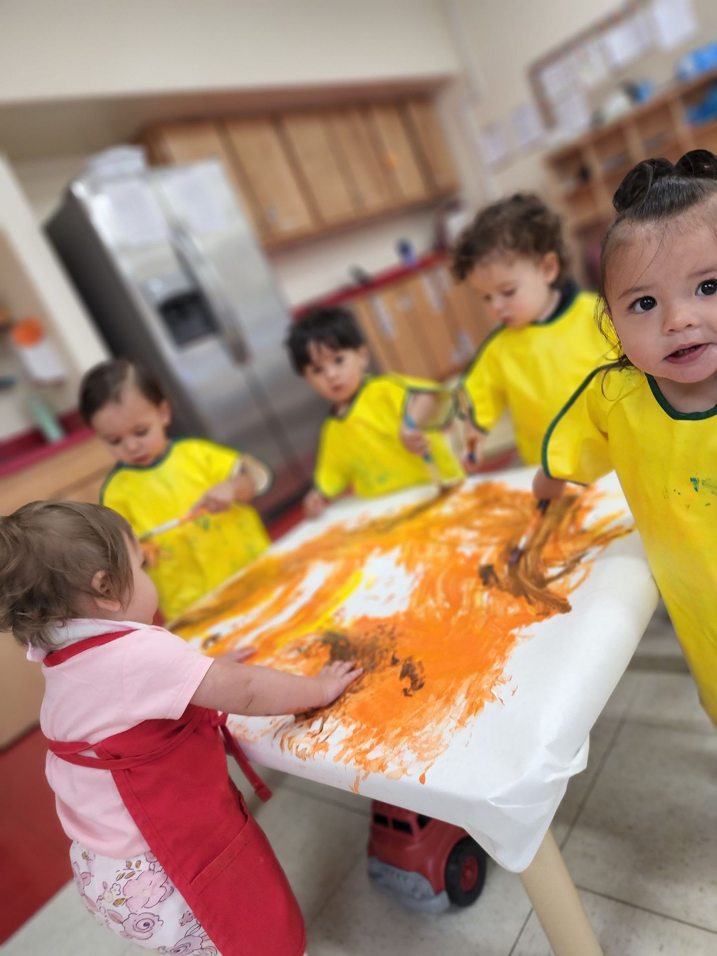 a group of young children are painting on a table .
