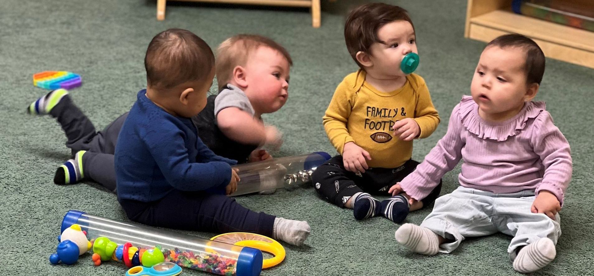 a group of babies are sitting on the floor playing with toys .