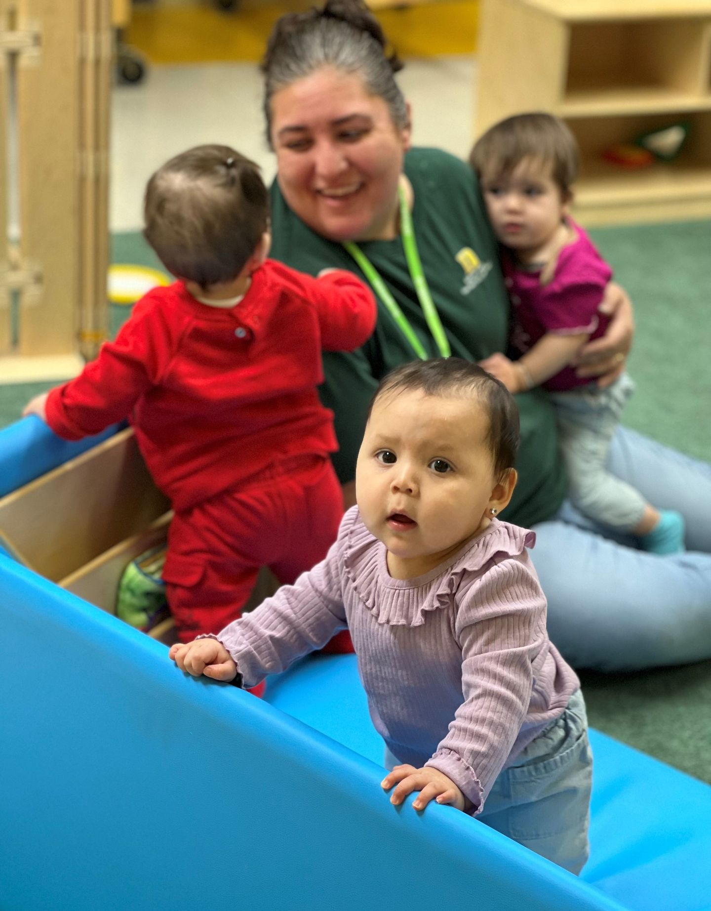 a woman is playing with three babies in a play room .
