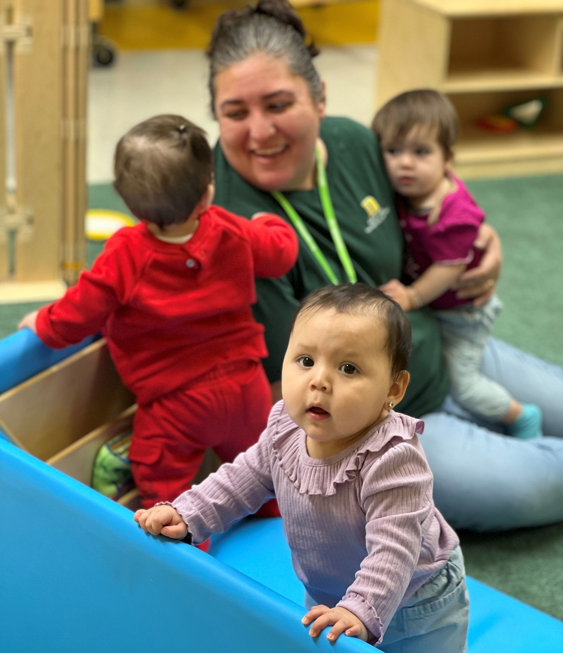 a woman is playing with two babies on a blue slide .