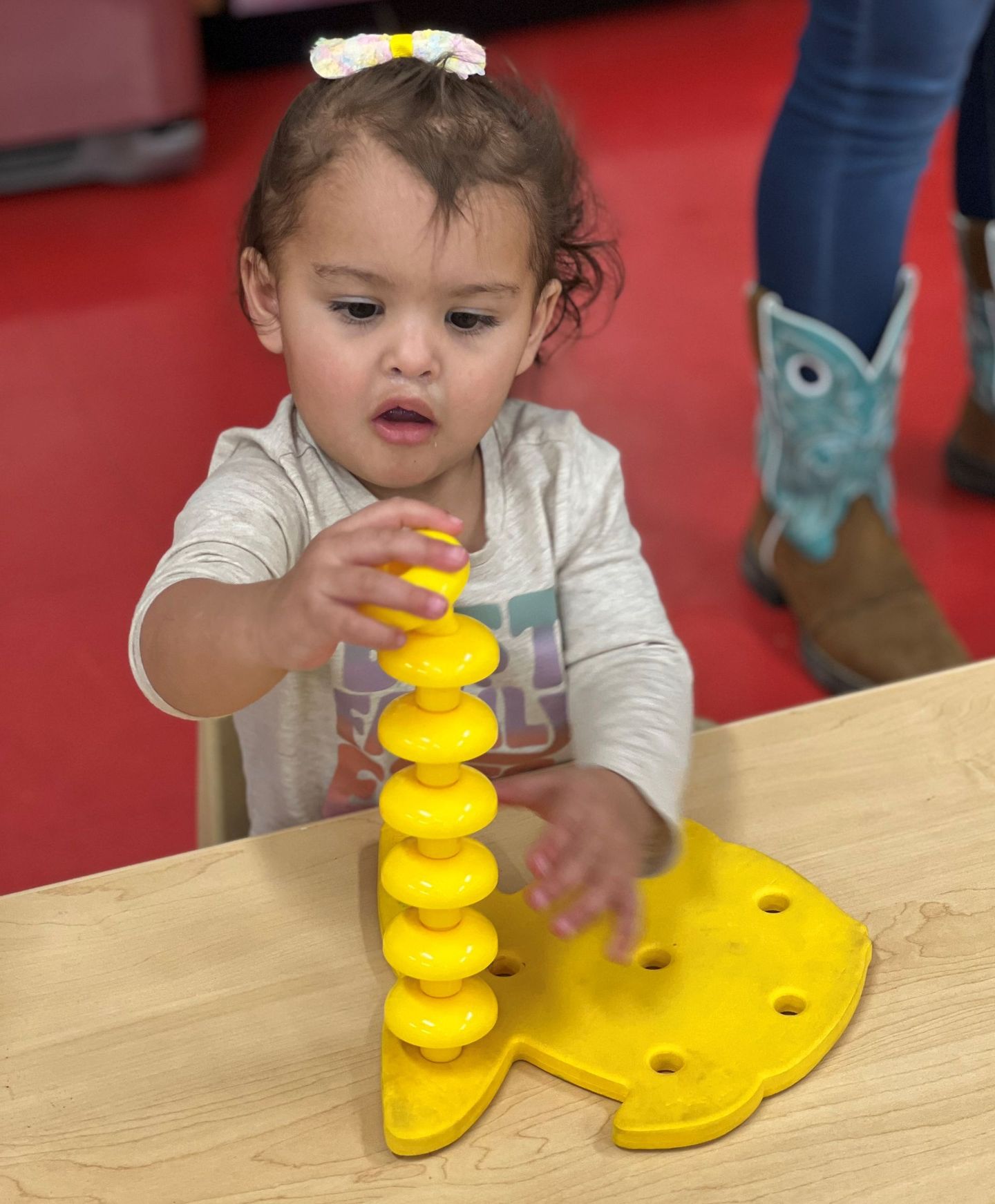 a little girl is playing with a yellow toy on a table .