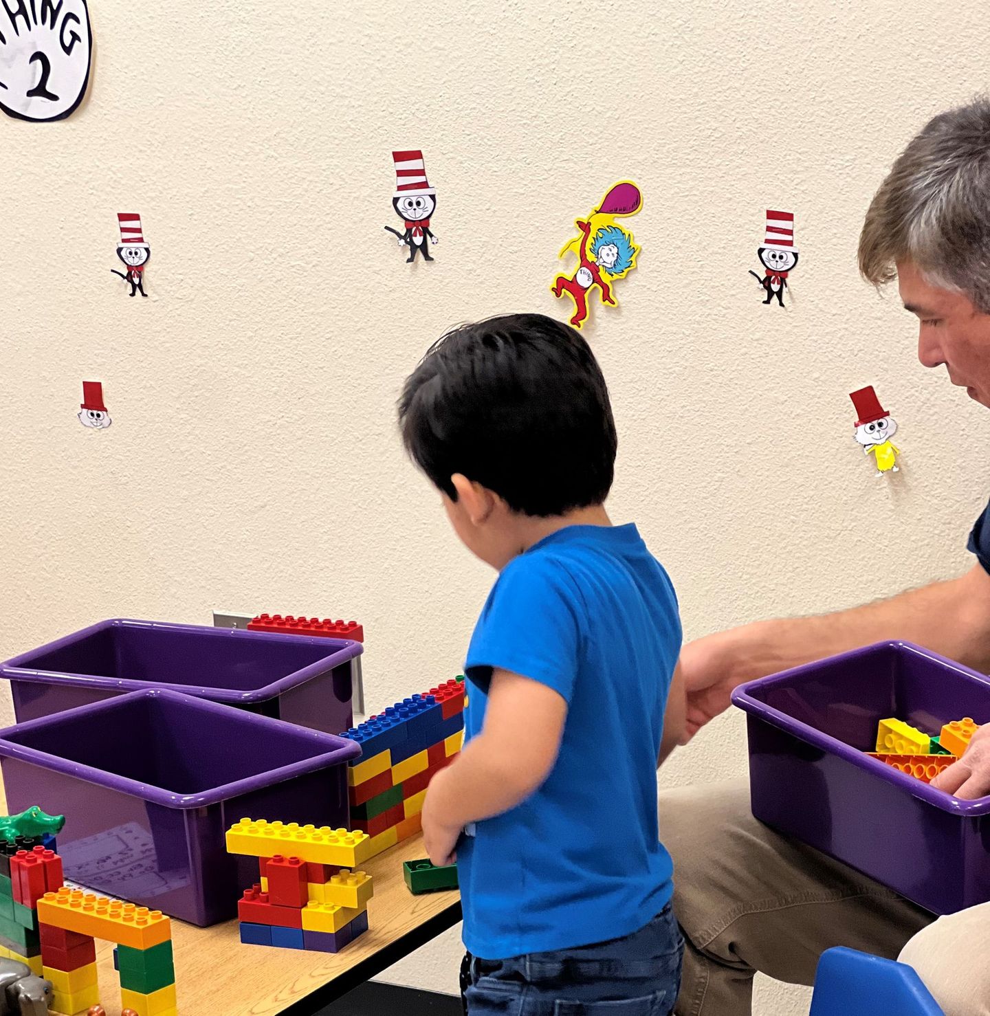a man and a child are playing with lego blocks on a table