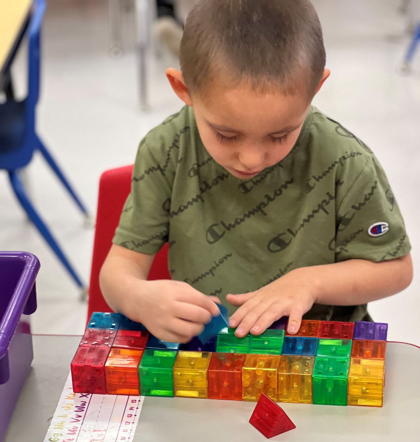 a young boy wearing a champion shirt is playing with blocks