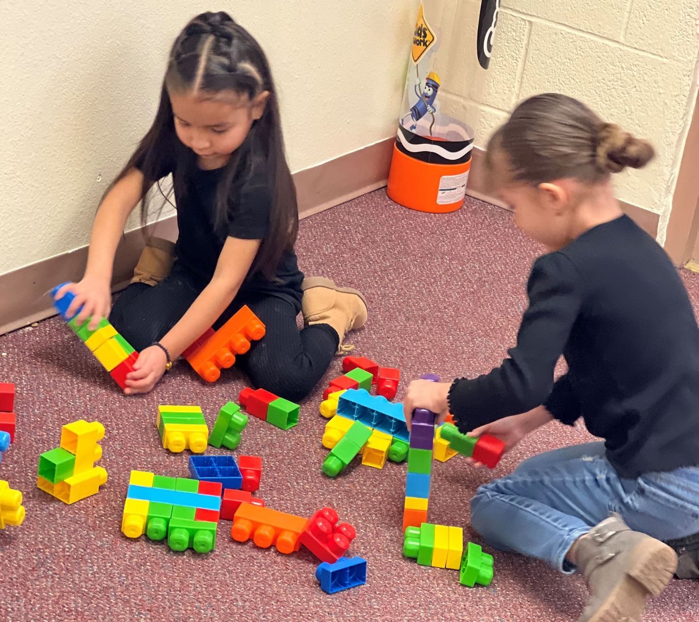 two young girls are playing with lego blocks on the floor