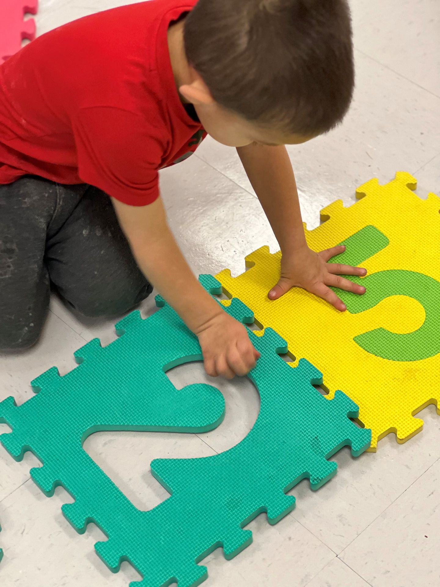 a young boy is playing with a puzzle mat on the floor .
