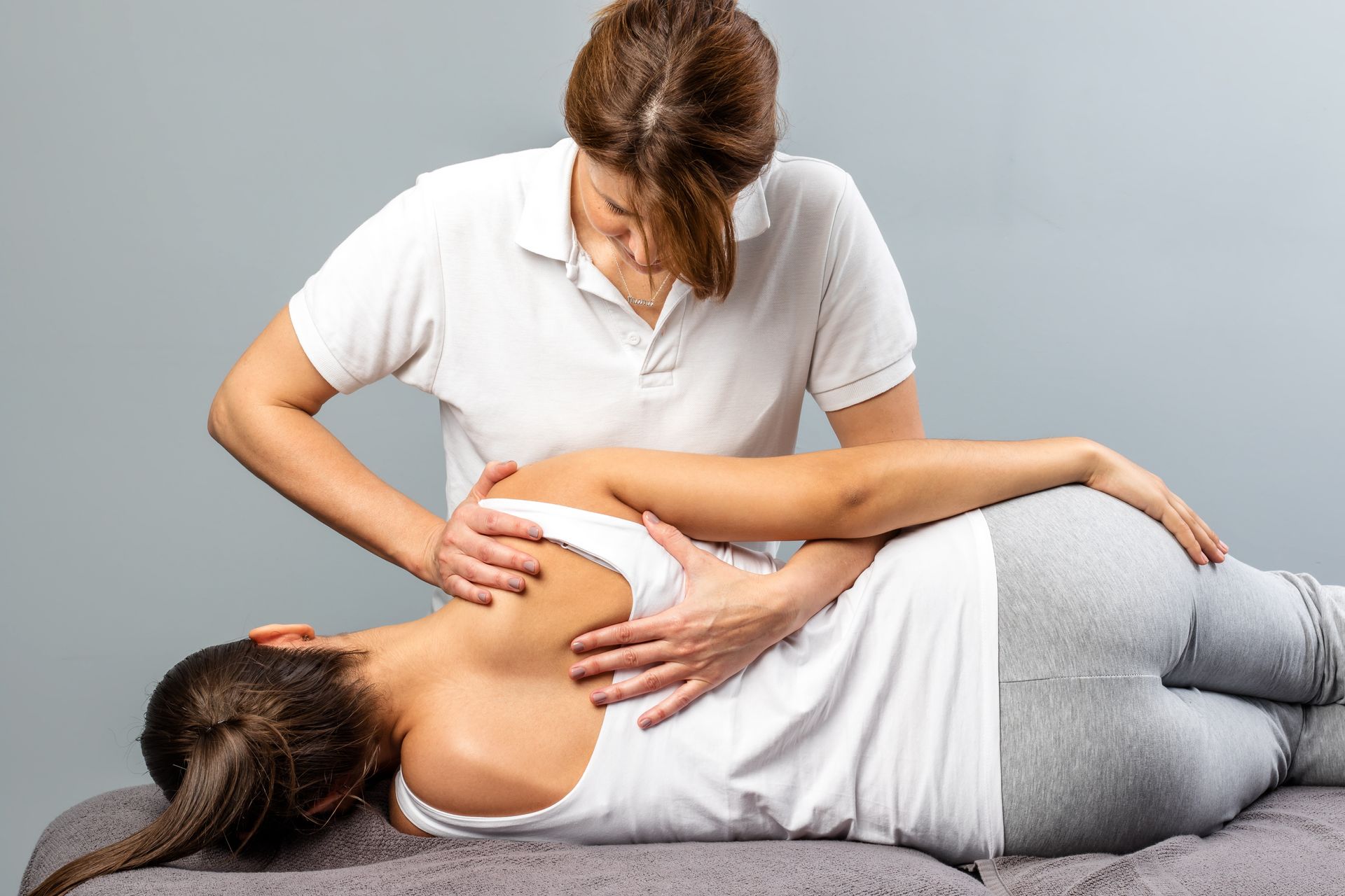 A physical therapist performing a lower back adjustment during a professional treatment session.
