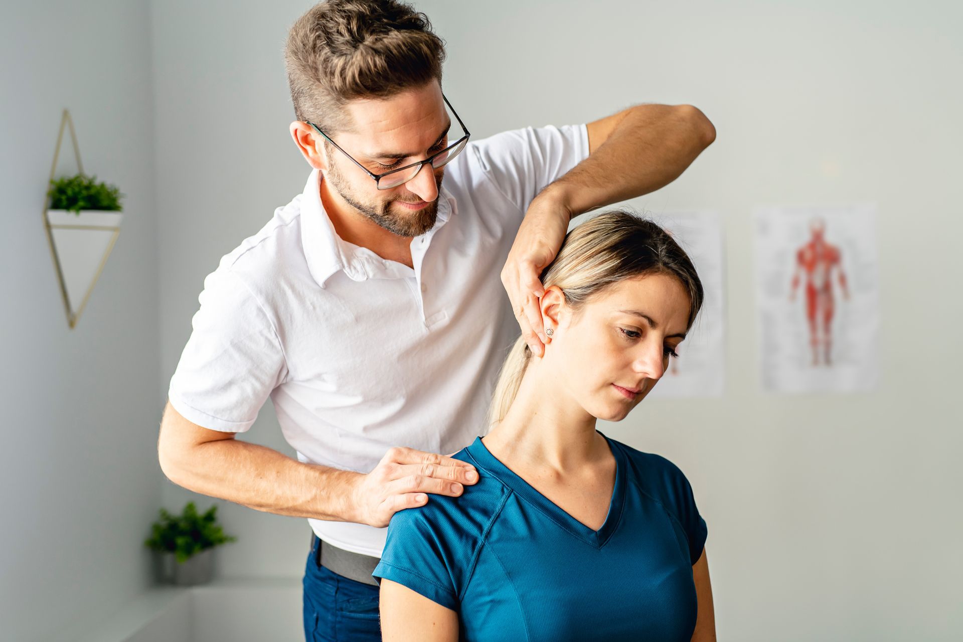 Manual neck and shoulder adjustment performed by a chiropractor in a medical office.