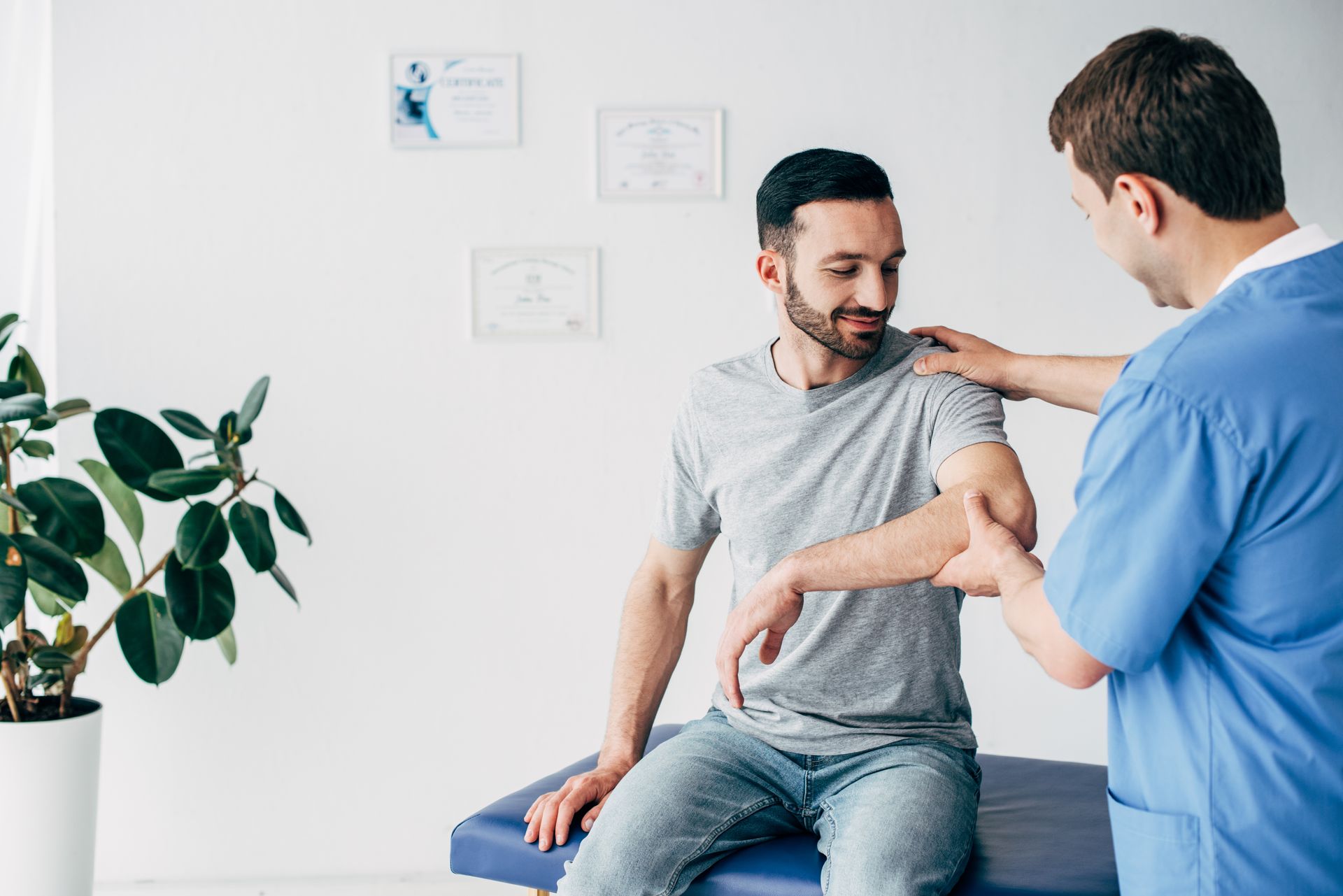 Healthcare provider examining a patient’s arm during a physical therapy consultation.