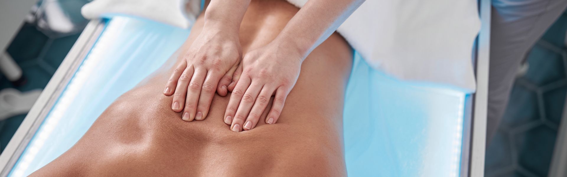 Chiropractic therapist massages the back of a male patient in a contemporary clinic office.