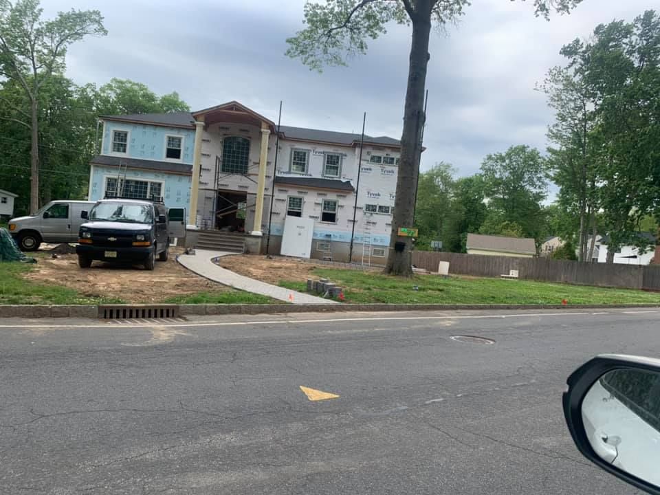 House under construction, light blue siding, white trim, with a van and truck parked in front.