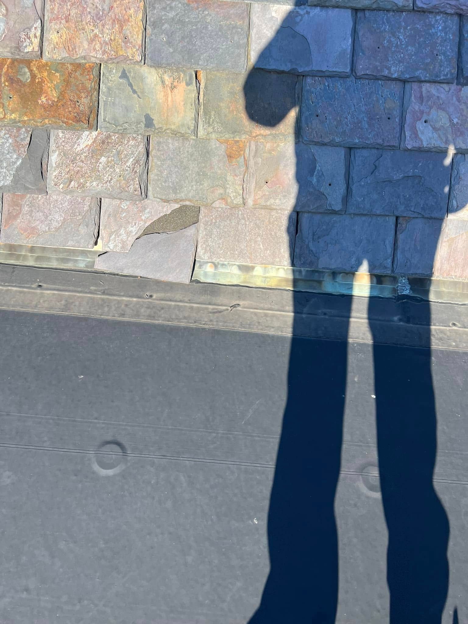 Shadow of a person standing on textured surface; brick wall backdrop.