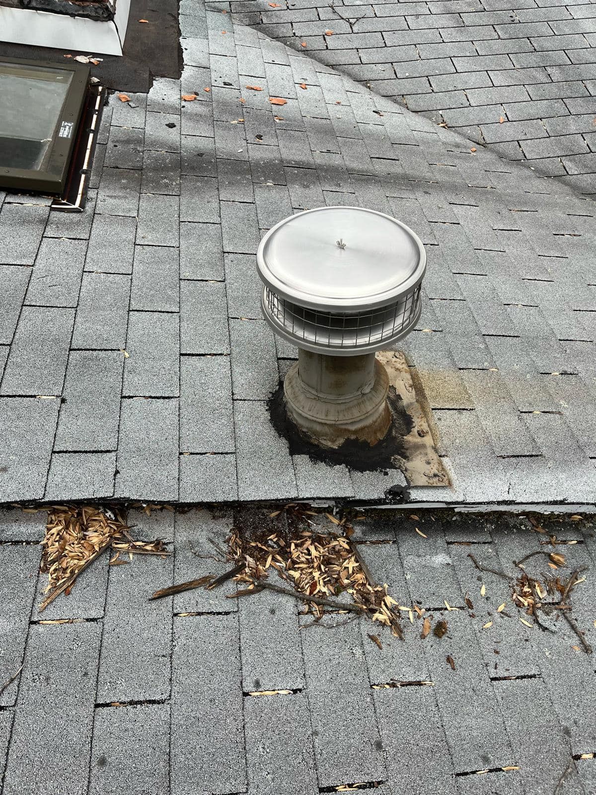 Roof with a vent and damaged shingles.
