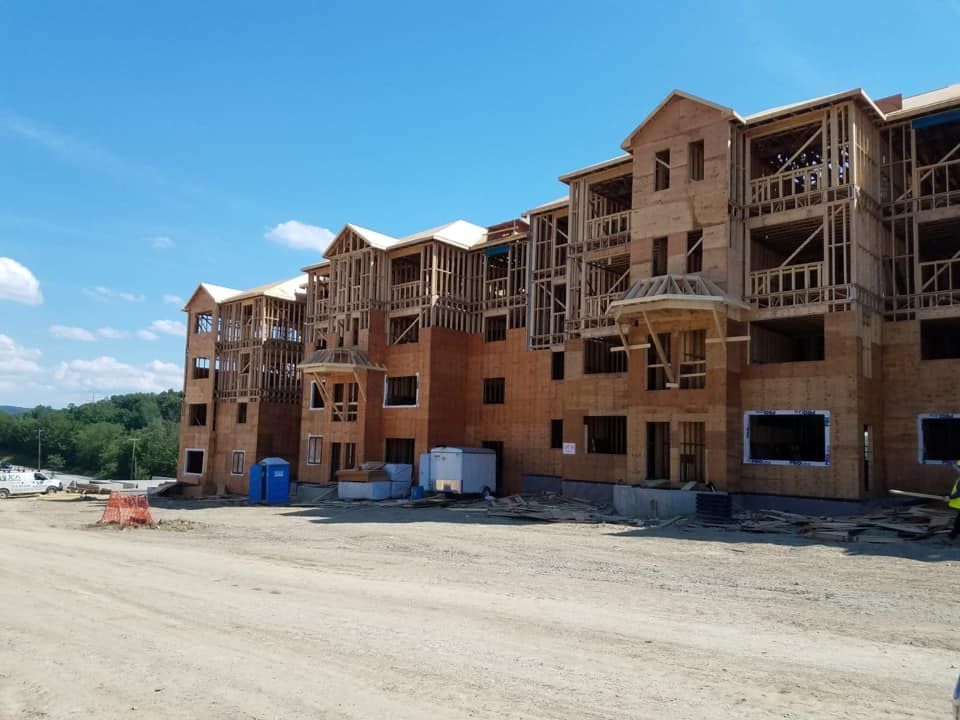 Multi-story apartment building under construction, wooden frame, blue sky.