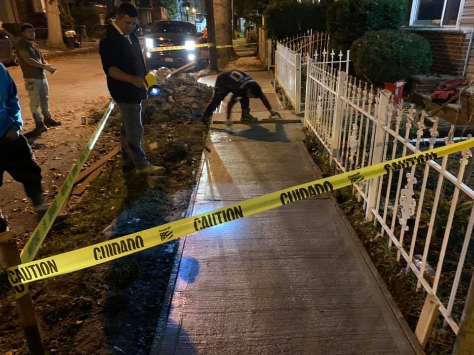 Crime scene marked with caution tape; individuals investigate sidewalk at night.